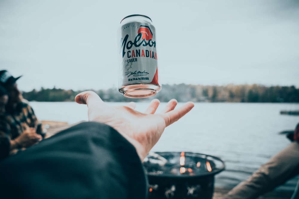 person tossing easy-open beer can