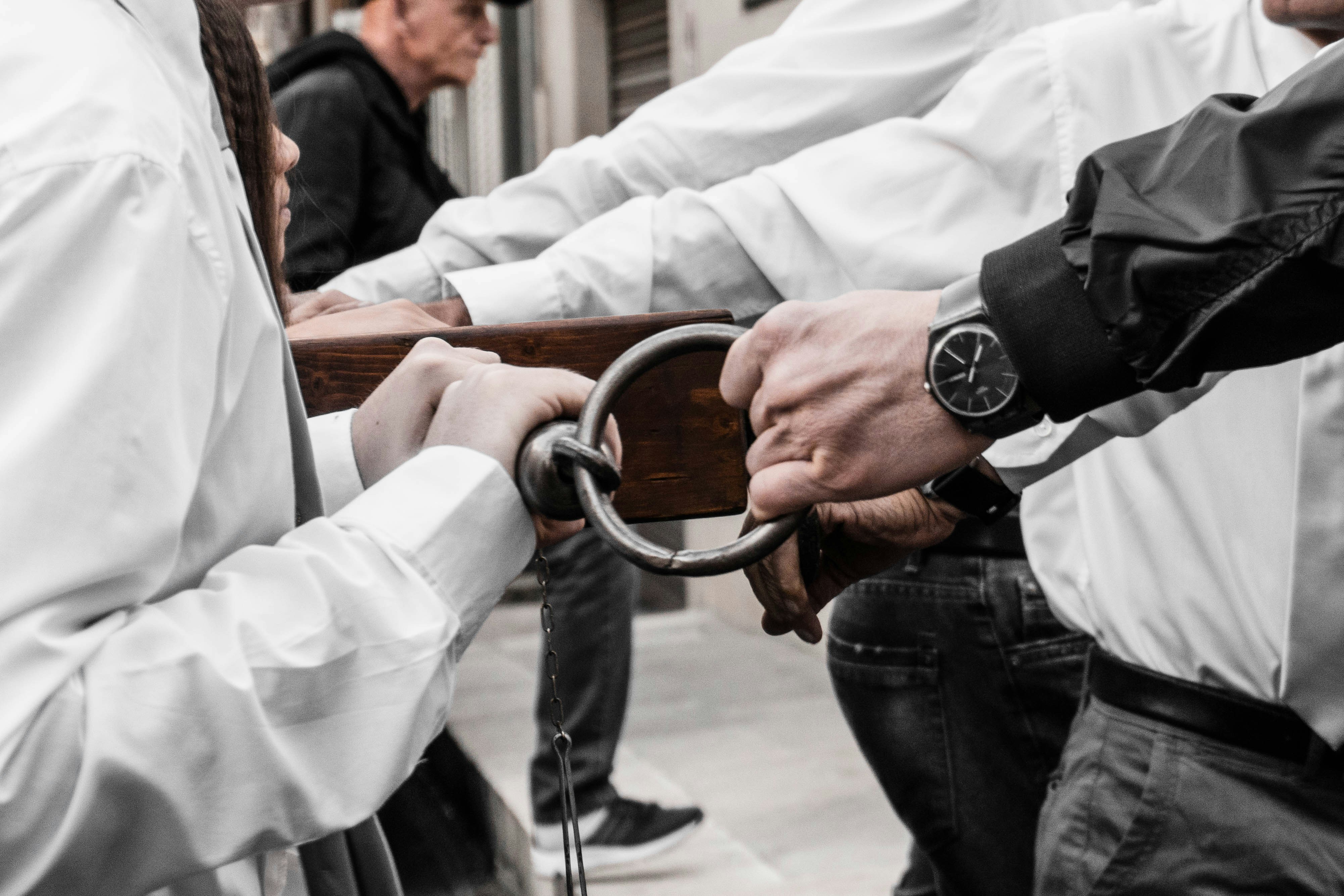 A pair of hands in handcuffs, with a blurred police uniform in the background, symbolizing justice being served.