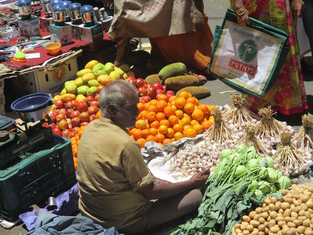 Homme assis près de l’étalage de fruits et légumes