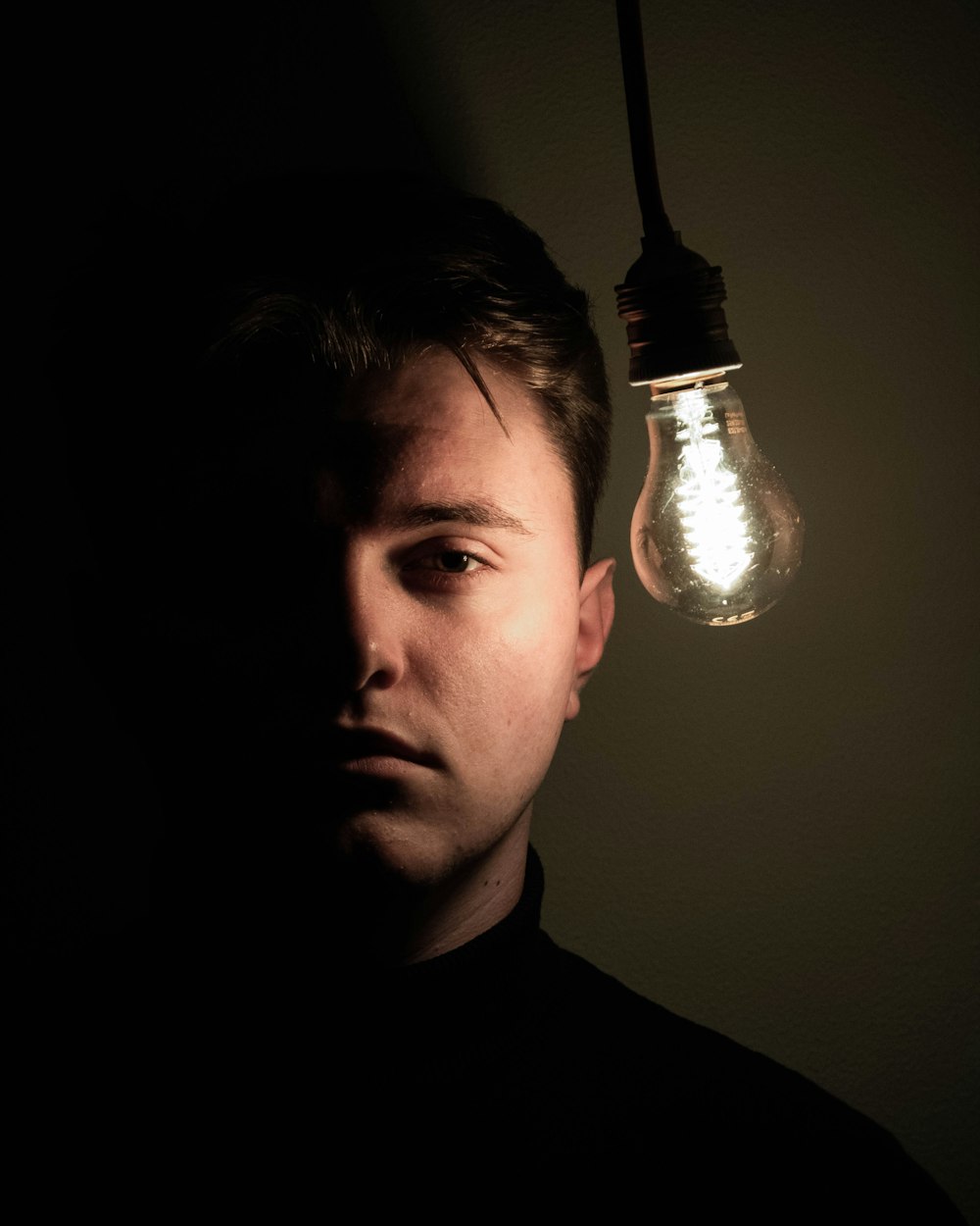 man standing beside lighted light bulb