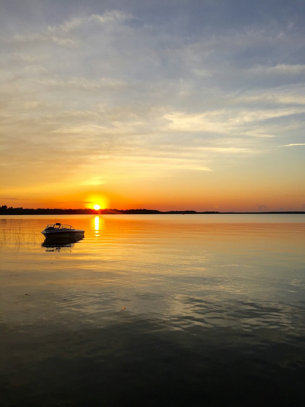 boat adrift away from shore during sunset