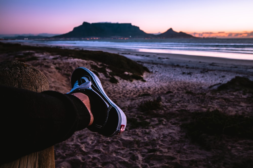 person wearing black Vans Old Skool shoe near shore