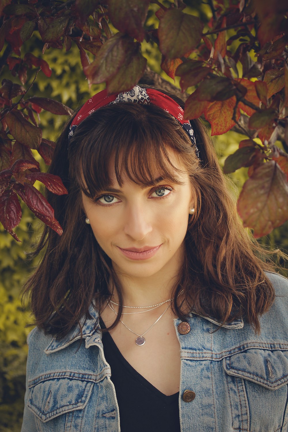 woman wearing denim jacket standing under leaves