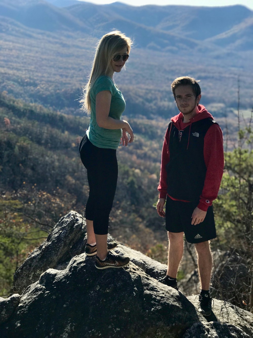 man and woman standing on rock outdoor during daytime