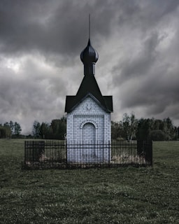 white concrete building with metal fence on field