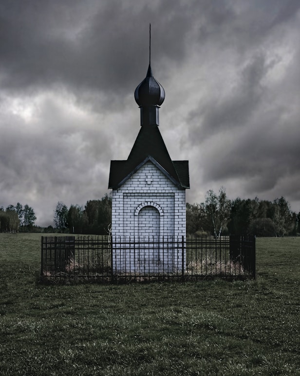 white concrete building with metal fence on field