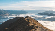 A serene mountain peak with a lone hiker admiring the expansive view.
