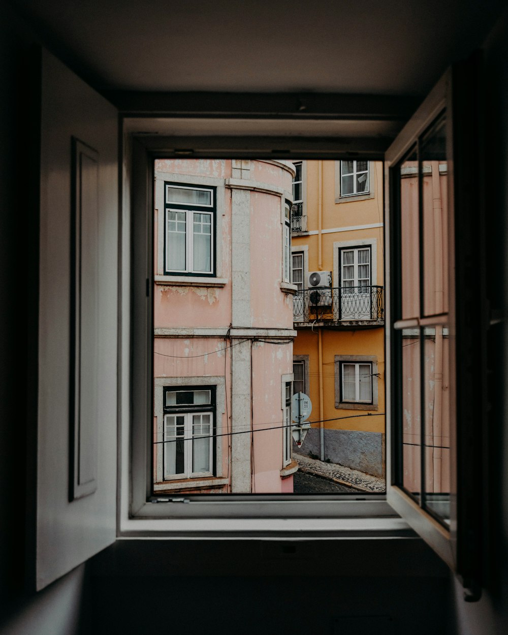janela de madeira aberta com vista para edifícios de concreto