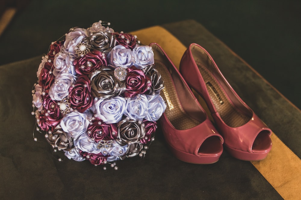 pair of maroon leather shoes beside flower boquet