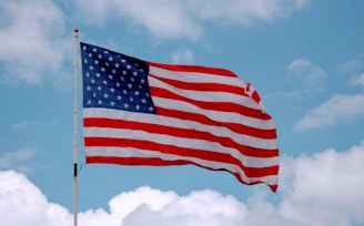 A waving American flag with a clear blue sky background symbolizing patriotism.
