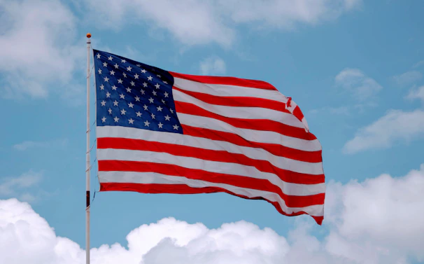 A proud individual taking the U.S. citizenship oath with the American flag in the background.