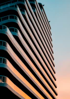 Wide shot of a sleek modern residential building at sunset, showcasing clean lines and refined architecture.