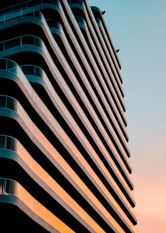 Sunset view of a completed residential building with clean lines and rich blue accents highlighting the structure.