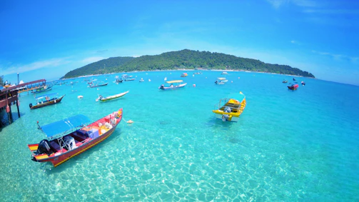 A vibrant coastal scene with boats bobbing on turquoise waters near sandy beaches.