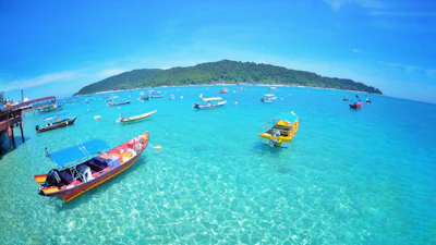 A vibrant beach scene with turquoise waters and traditional fishing boats.