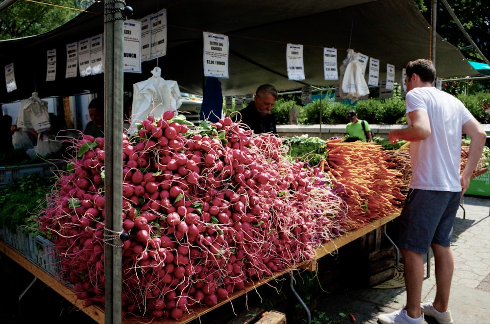 man standing beside vegetables display