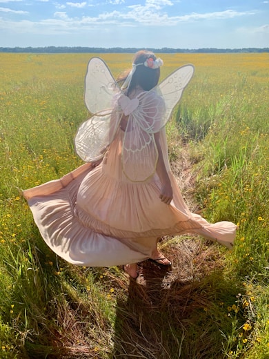 woman in fairy costume standing on green field