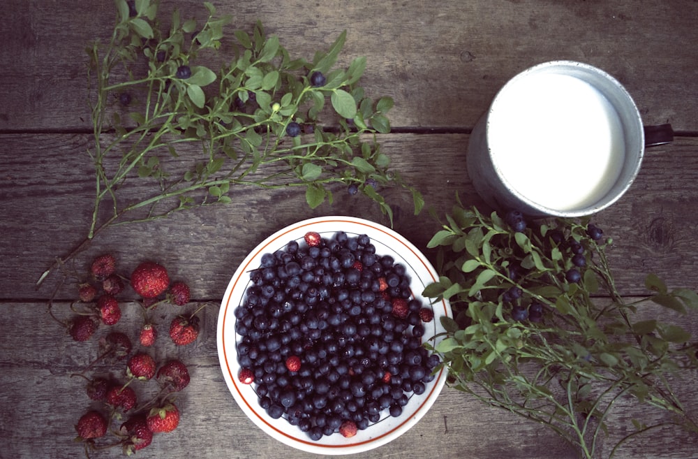 blackberries in round white ceramic plate near white plastic bowl