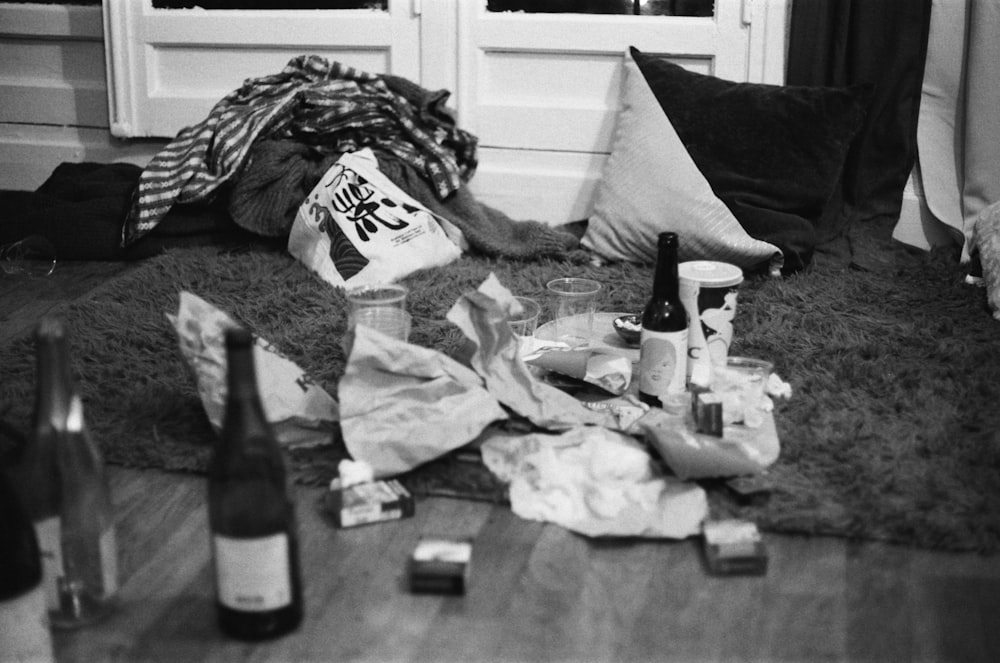grayscale photography of bottles and papers on area rug