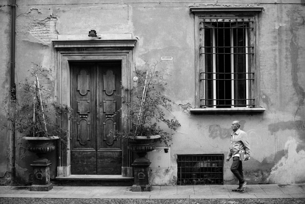 grayscale photo of man walking near door