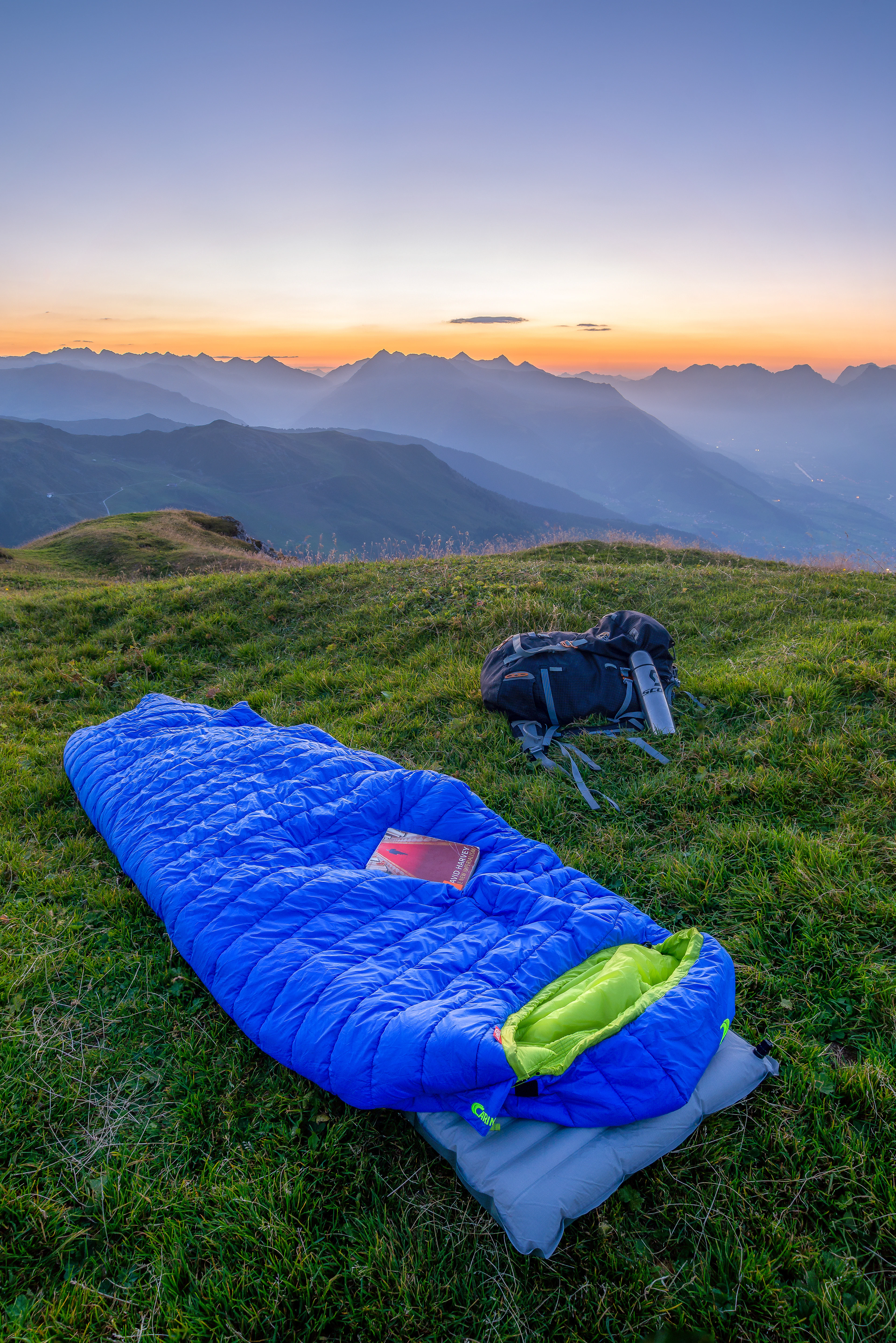 A blue sleeping bag on a grassy mountainside