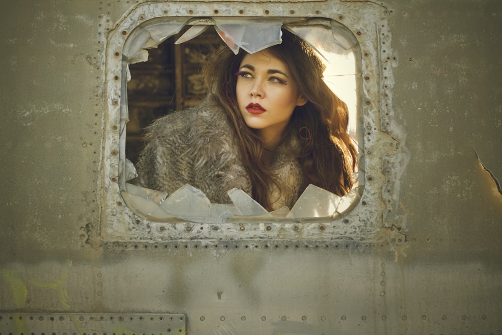 woman seated near broken glass window