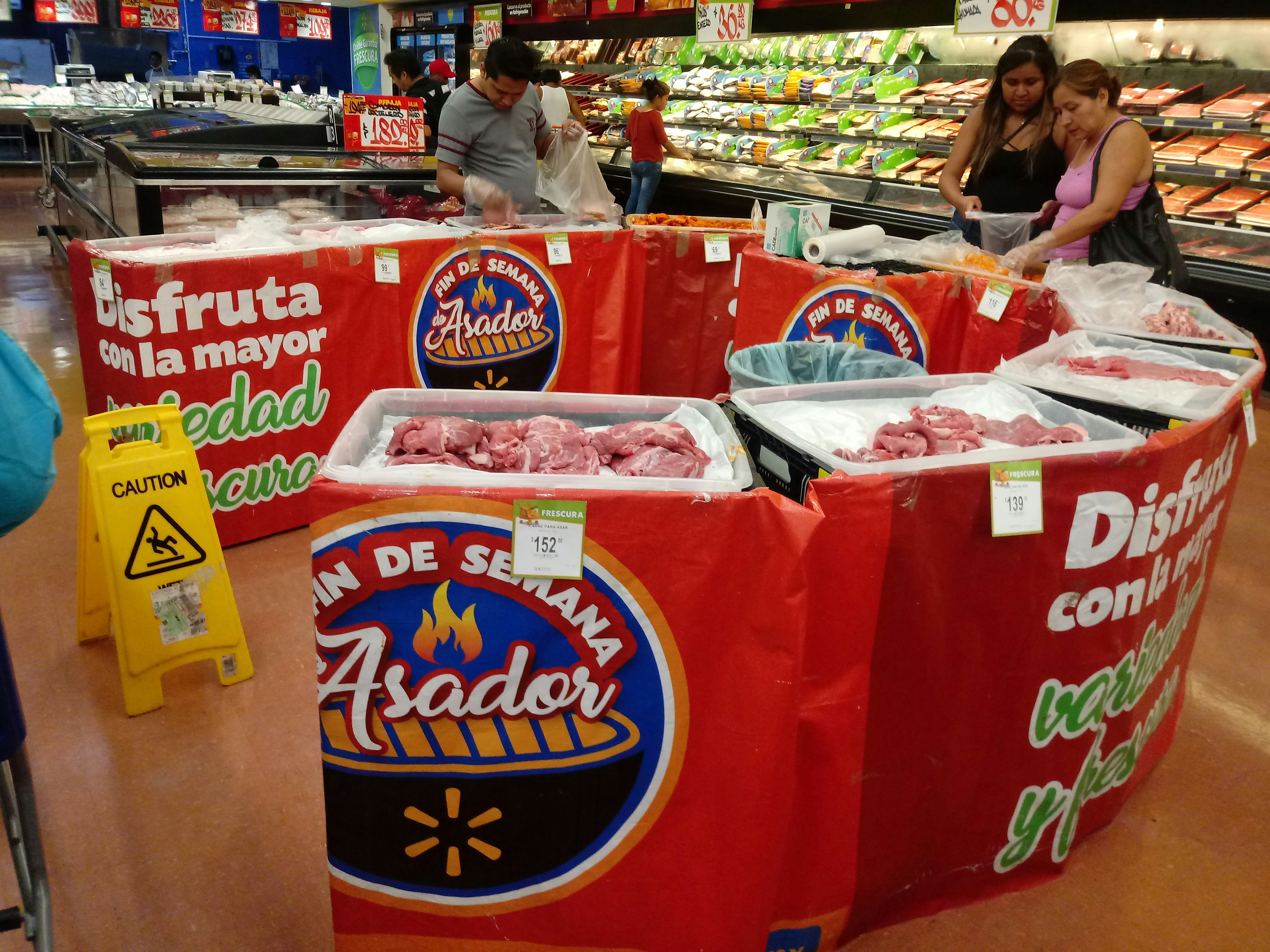personnes debout à côté de viandes crues dans un marché latéral