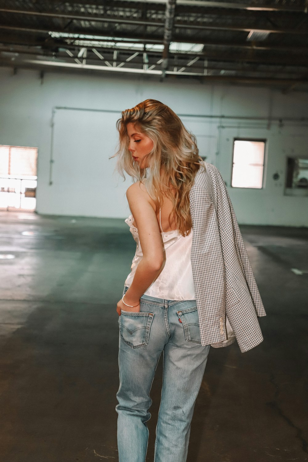 woman in white tank top and blue denim jeans walking