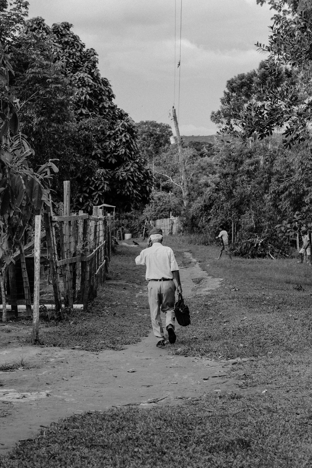 man walking beside fence near trees