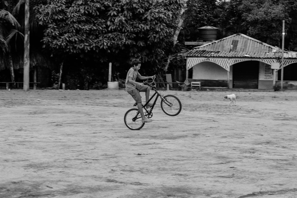 grayscale photo of boy doing exhibition with bike