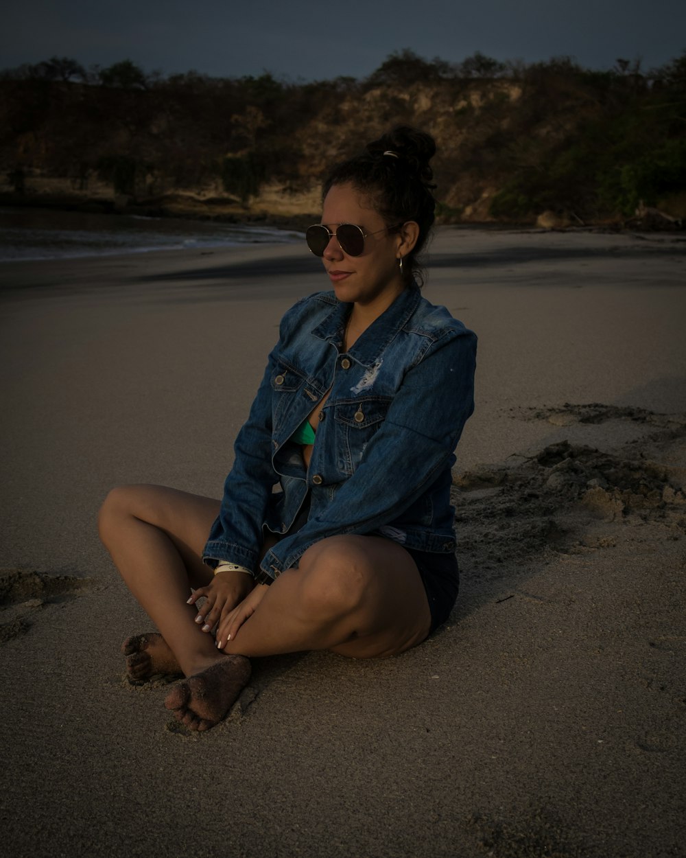 woman sitting on sand near seashore