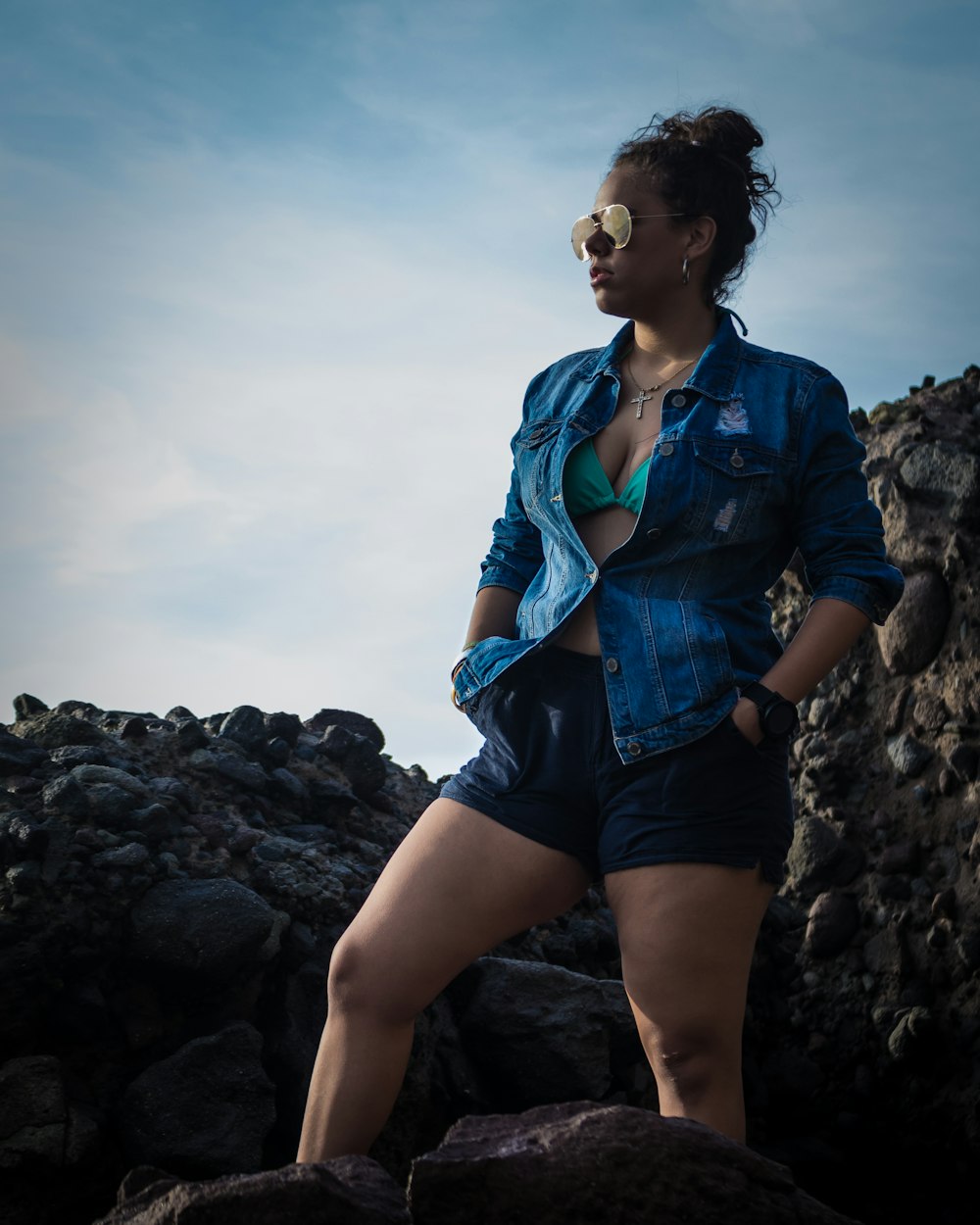 woman in blue button-up t-shirt standing near rocks