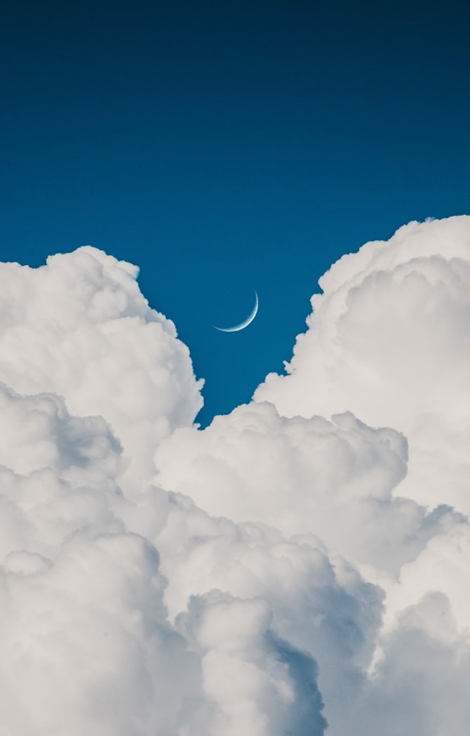 clouds and crescent moon during daytime