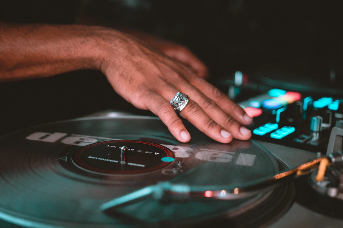 Hand touching a vinyl record on a DJ mixer