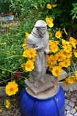 A charming garden statue surrounded by flowers.