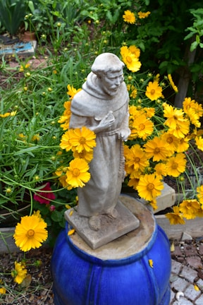 A charming garden statue surrounded by flowers.