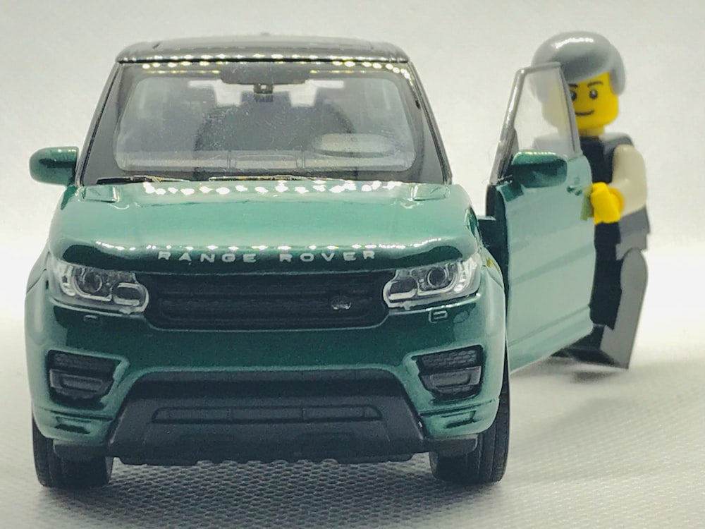 modello in scala di SUV Range Rover verde con minifig in piedi alla portiera aperta