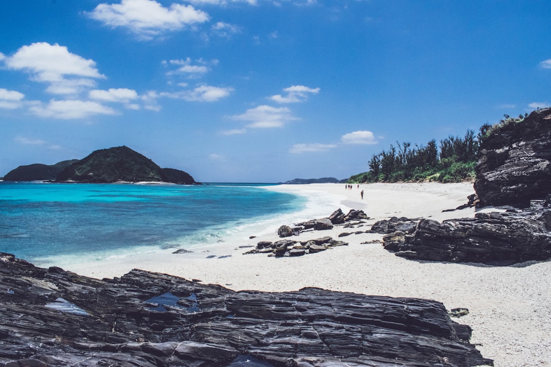 people walking in seashore near mountain, Furuzamami Beach in Zamami Island (Okinawa) in Japan.