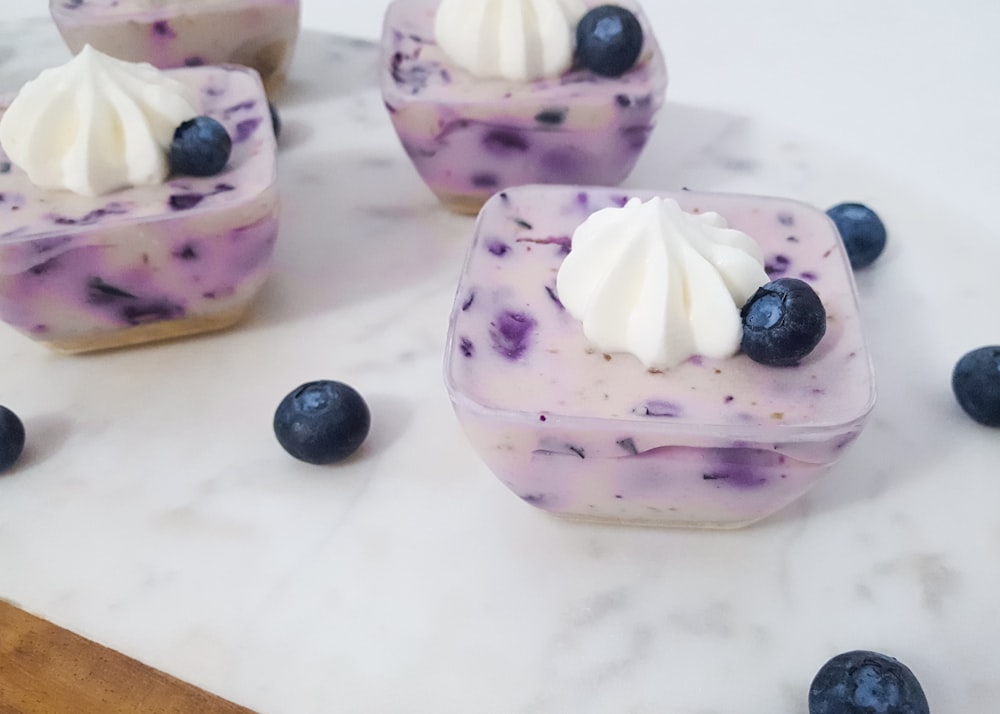 four square pastries with icing and blueberry on top