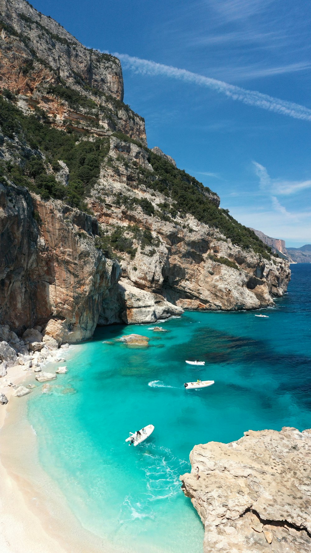 Montanha cinza e verde ao lado do mar durante o dia