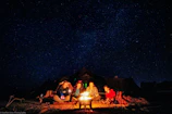 A group of travelers sharing stories around a campfire under a starry sky in rural Europe.