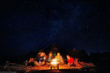 Travelers sharing a quiet moment around a campfire under a starry African night