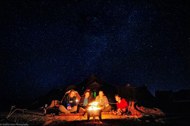 Students laughing together around a campfire on a goglobe student trip under a starry sky.