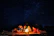 A vibrant photo of a small group gathered around a campfire under a starry desert sky during a Sindhventure expedition.