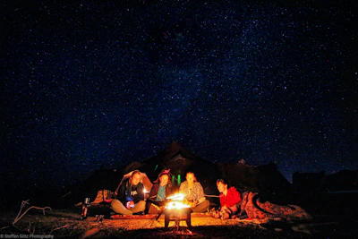 A warm family gathering around a campfire under a starry sky at the glamping site.