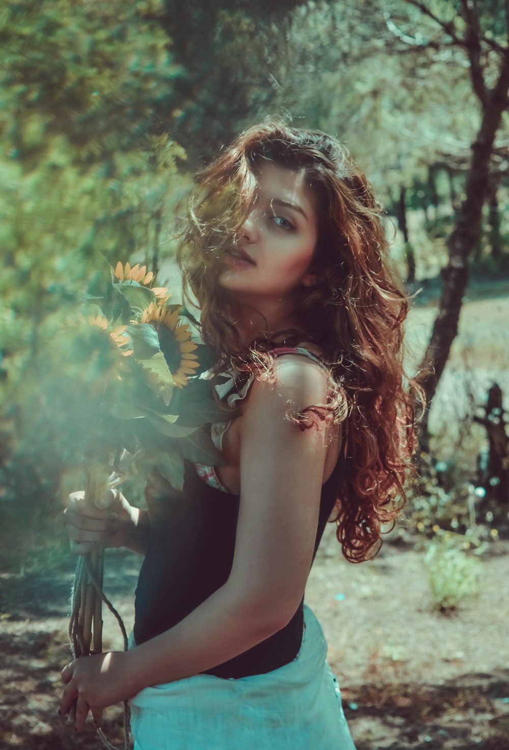 woman in black sleeveless top holding sunflowers