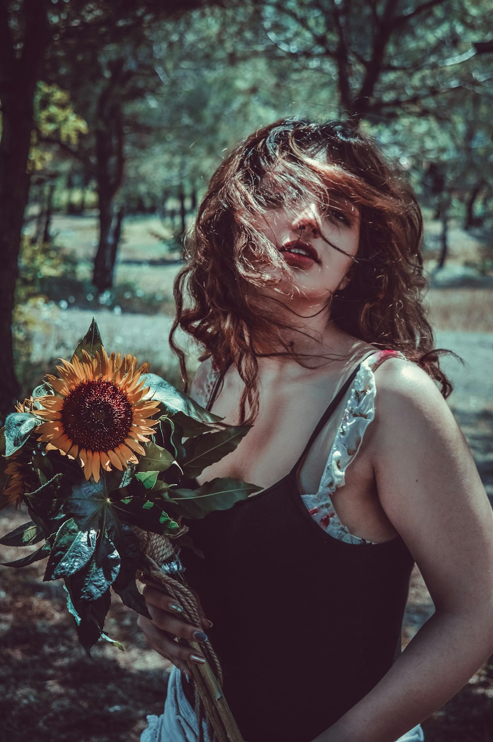 a woman in a black dress holding a sunflower