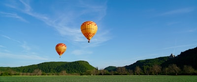 A couple enjoying a private hot air balloon ride above lush green valleys.