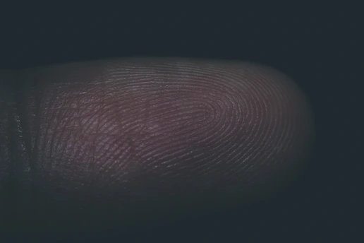 Close-up of a forensic investigator examining fingerprint patterns under specialized lighting.