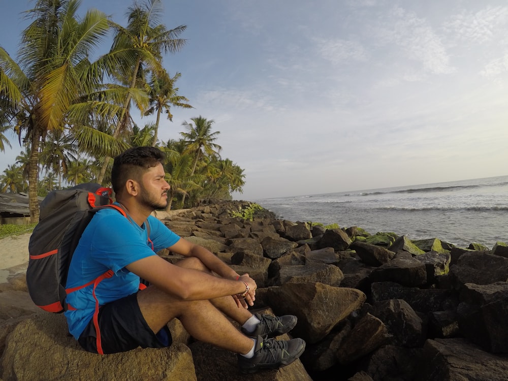 a man sitting on a rock near the ocean